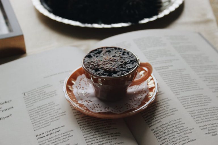 Cup of coffee on an open book, creating a cozy reading atmosphere with a porcelain cup.