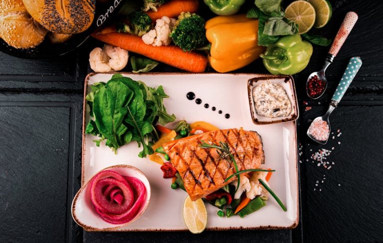 Top view of grilled salmon served with vegetables, herbs, and fresh bread. Perfect for a healthy meal.