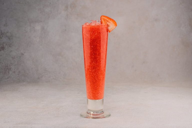 Tall glass of strawberry cocktail with ice, perfect for refreshing summer treats in a studio setting.