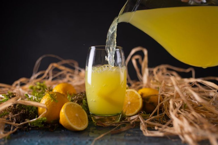 Vibrant lemonade poured into a glass surrounded by fresh lemons on a rustic background.