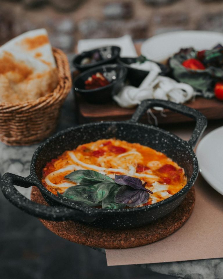 A close-up of delicious shakshuka served in a rustic iron pan with fresh basil in Antalya, Türkiye.
