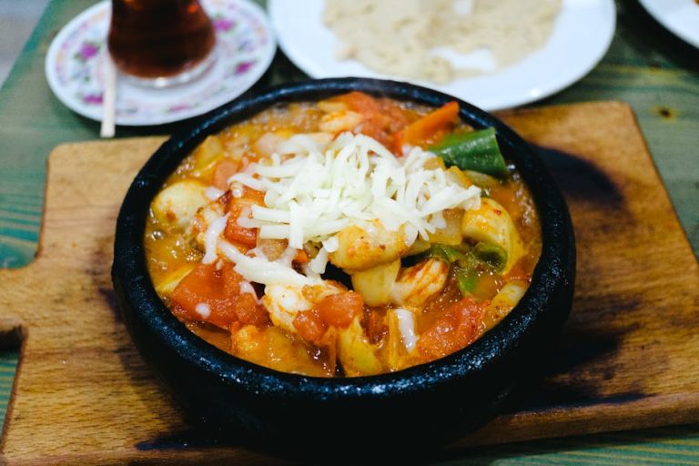 Savory shrimp and vegetable casserole topped with cheese, served on a rustic wooden board.