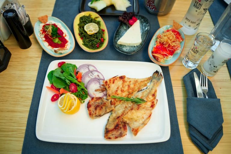 Delicious Mediterranean meal featuring grilled fish, fresh salad, and traditional sides.