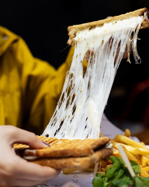 Close-up of a gooey cheese pull from a grilled sandwich with fries, perfect comfort food shot.