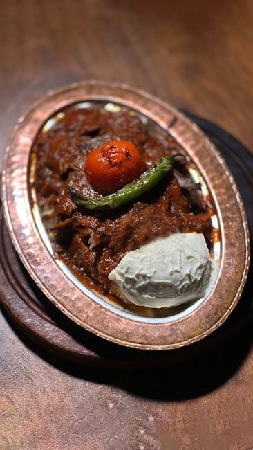 Authentic Turkish Iskender kebab with yogurt, grilled tomato, and pepper on copper plate.