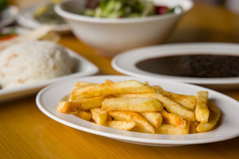 Delicious crispy french fries on a white plate served with assorted dishes.